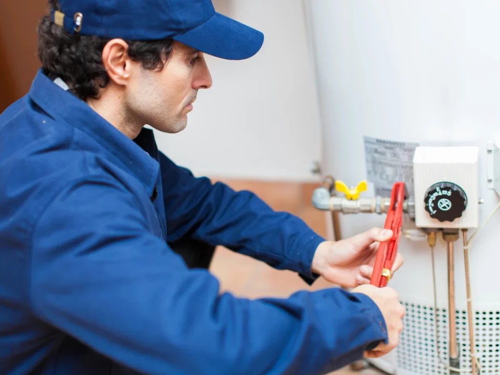 A close-up shot of a professional plumber repairing a whistling water heater.