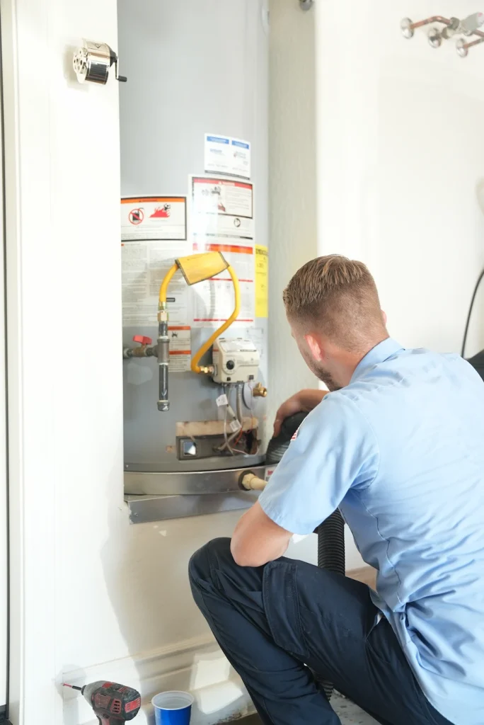 A professional plumber from Patriotic Plumbing repairs a water heater. 