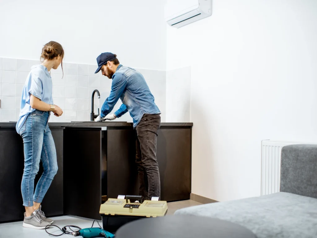 A plumber fixes a leak in the kitchen sink.